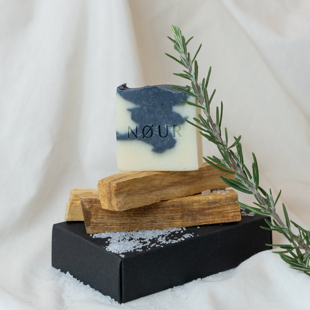 nour seife volcano dekoriert mit rosmarinzweig holzstücke und salz auf schwarzer box