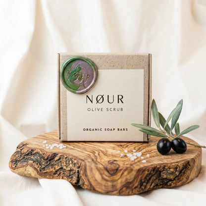 Verpackung von Olive Scrub auf einem Olivenholzbrett mit Oliven und Salz