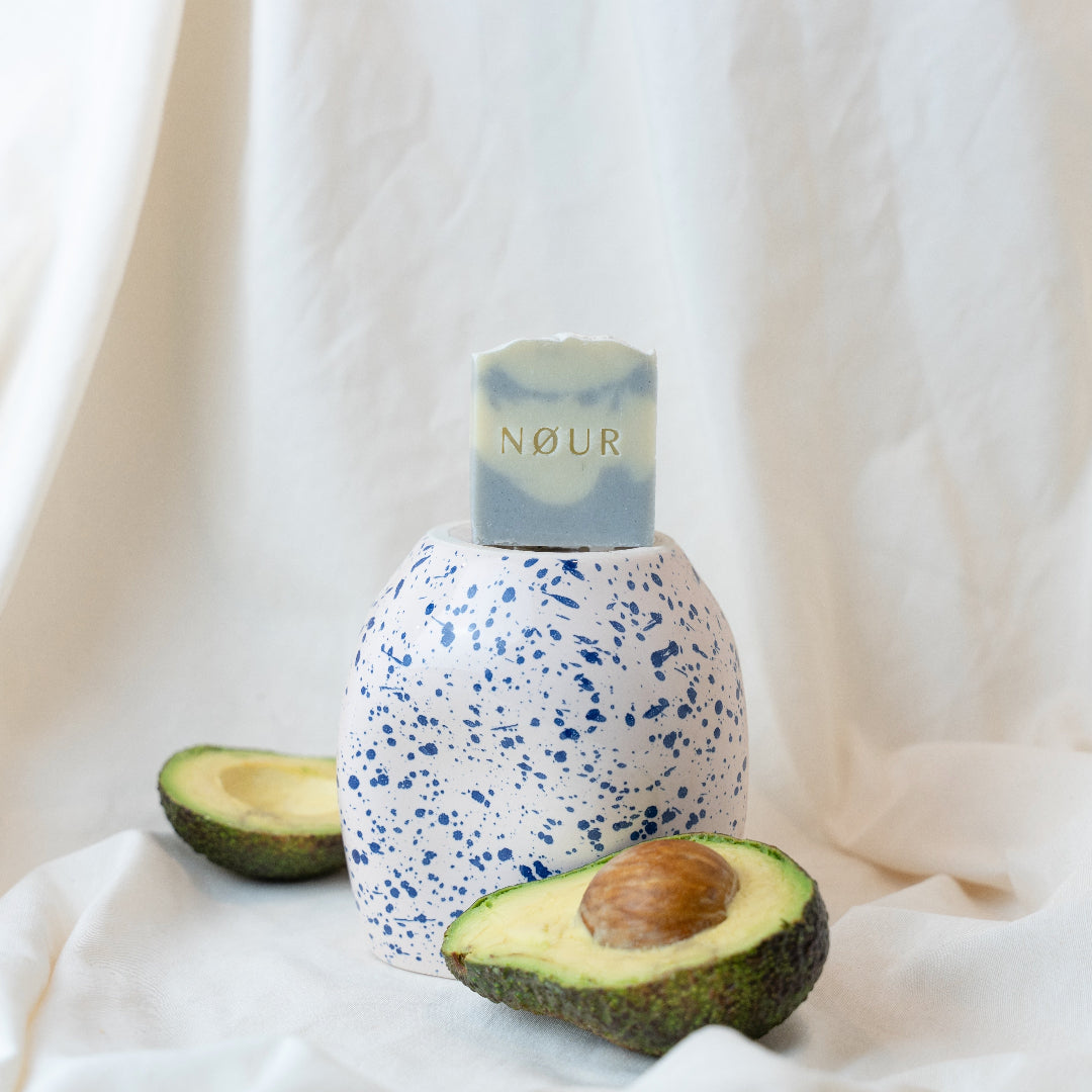 Cloud-Seife auf blau-weißer Vase mit halber Avocado 