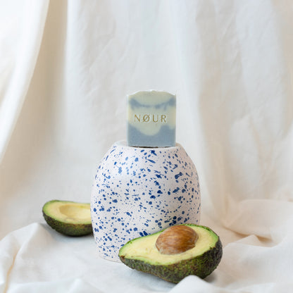 Cloud-Seife auf blau-weißer Vase mit halber Avocado 